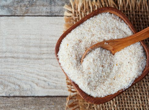 Psyllium (ispaghula) husk in wooden bowl on rustic background. Top view with copy space