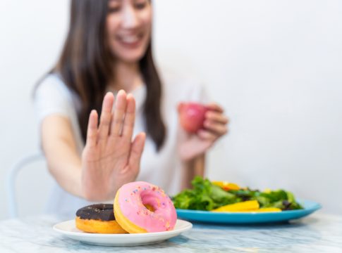 Asian young woman refuse junk food while choose to eat healthy salad and fruit juice for her healthy. Girl take care of herself by having high nutrition food every day. Good food for healthy concept.