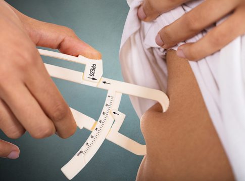 Close-up Of A Woman's Hand Checking Stomach Fat With Caliper