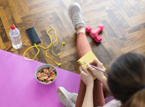 Young sporty woman writing workout plan in notebook after a workout