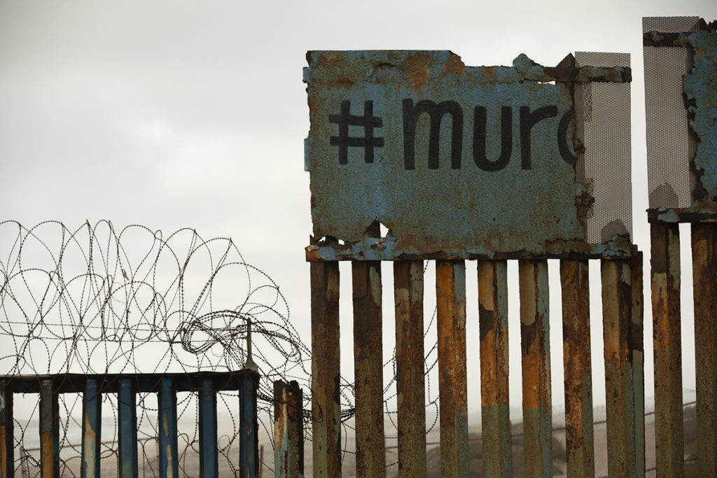 Tijuana, Baja California / Mexico - April 11, 2021: Graffiti spelling out "wall" in Spanish covers a portion of the USA and Mexico border wall. Tijuana, Baja California / Mexico - April 11, 2021: Graffiti spelling out "wall" in Spanish covers a portion of the USA and Mexico border wall.