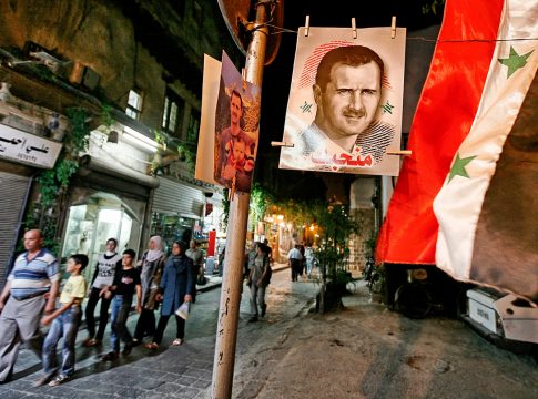 Damascus,Syria - August 04,2010 : Pre-war Syria.A poster of Syrian president Bashar al-Assad hangs in front of a shop in the old city of Damascus.Syrian flags.The number of Syrians who fled the Civil War grew to 4 million 185 thousand.