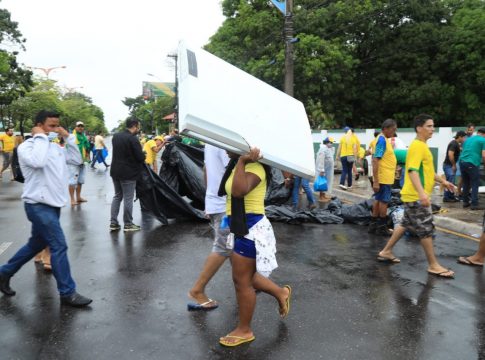 Manifestante leva porta de uma geladeira enquanto as forças de segurança fazem a desobstrução da calçada. Foto: Mácio Ferreira/Agência Belém/Comus