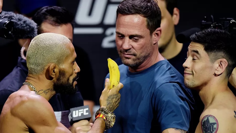 Deiveson Figueiredo mostra banana para Brandon Moreno, durante a pesagem do UFC 283, em resposta a um treinador do rival acusado de racismo. Foto: Alexandre Loureiro-UFC